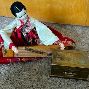 This is an antique Chinese doll with a locking chest